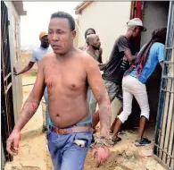  ?? PICTURE: BOXER NGWENYA ?? INJURED: A badly burnt man leaves his spaza shop in Bramfische­rville after a petrol bomb was hurled into the premises. In the background are residents rushing in to loot the store.