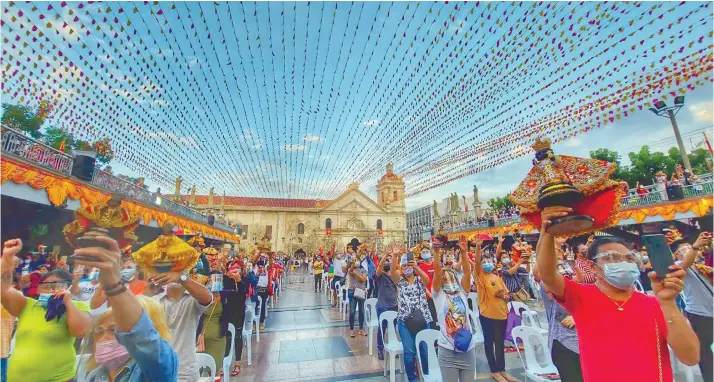  ?? / AMPER CAMPAÑA ?? IN-PERSON WORSHIP. Devotees, wearing masks and face shields, wave and hold images of the Sto. Niño aloft during the Hubo mass, which signals the end of the Fiesta Señor, on Friday, Jan. 22, 2021 at the Pilgrim Center.