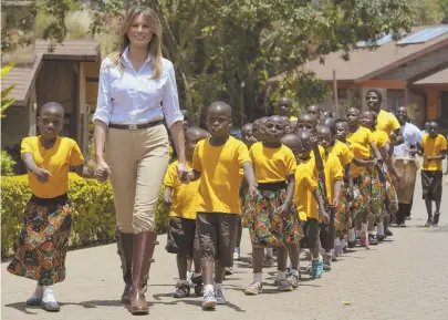  ?? AP PHOTOS ?? SPECIAL GUEST: First lady Melania Trump walks with children from the Nest Orphanage in Limuru, Kenya, yesterday. Earlier, the children greeted her with songs and dances. Below, the first lady visits Nairobi National Park in Nairobi, Kenya, guided by Nelly Palmeris, right.