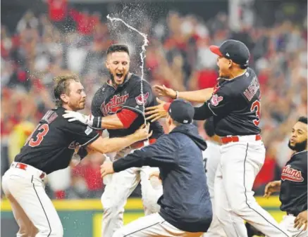  ?? Jason Miller, Getty Images ?? Yan Gomes, center, celebrates with his teammates Friday in Cleveland after hitting an RBI single in the 13th inning, giving the defending American League champion Indians a 9-8 victory over the Yankees in Game 2 of their ALDS.