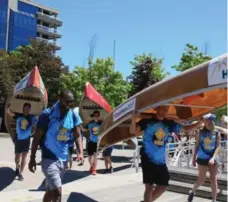  ?? ALYSHAH HASHAM PHOTOS/TORONTO STAR ?? More than 100 former campers carry canoes through downtown Toronto Saturday for the annual Amici’s Canoe Heads for Kids fundraiser.