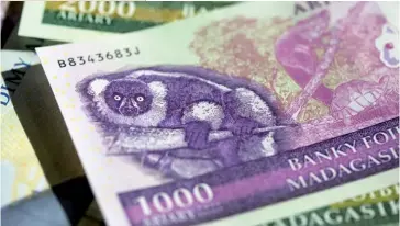  ??  ?? Photo ci-dessus : Billet de banque malgache. Alors que Madagascar a fait partie intégrante de la Zone franc de 1960 à 1972, une nouvelle banque centrale a été créée à partir de 1973 avec une nouvelle monnaie : le franc malgache. Depuis juillet 2003, l’unité monétaire du pays est devenue l’ariary. (© Shuttersto­ck/Pearl-diver)