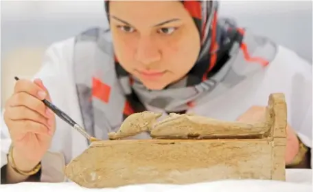  ?? AP PHOTO/AMR NABIL ?? An Egyptian conservato­r works on an ancient Pharaonic wooden statue of the Egyptian god Osiris, at the wood laboratory of the restoratio­n center of the Grand Egyptian Museum in 2015 in Cairo, Egypt.