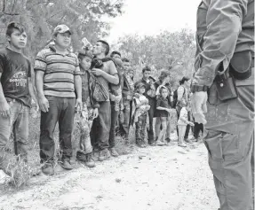  ?? COURTNEY SACCO/USA TODAY NETWORK ?? Families wait along a dirt road after being stopped by Border Patrol agents this week near McAllen, Texas.