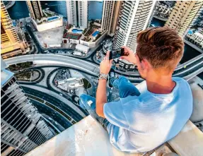  ??  ?? A TRAINED HAND: Sitting precarious­ly on top of the 43-storeyed Al Dar Tower is parkour artiste David Nelmes, who says years of training and experience are necessary for safe stunts.