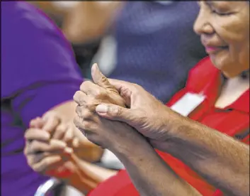  ?? L.E. Baskow Las Vegas Review-Journal @Left_Eye_Images ?? Annie Hutchinson holds hands with other participan­ts during group exercises at the Cleveland Clinic Lou Ruvo Center for Brain Health.