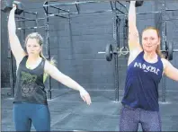  ?? MILLICENT MCKAY/JOURNAL PIONEER ?? Katrina Hutchinson, left, and Colleen Schurman complete dumbbell clean and jerks, one of the exercises in the open’s 18.1 workout.