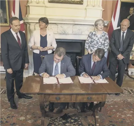  ?? PICTURE: GETTY ?? 0 DUP MP Jeffrey Donaldson, left, and Tory Chief Whip Gavin Williamson sign the deal in Downing Street watched by Arlene Foster, her deputy Nigel Dodds, Theresa May and First Secretary of State Damian Green