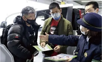  ?? The Yomiuri Shimbun ?? Police officers use leaflets to inform foreign tourists about snow-covered roads and road signs in Chitose, Hokkaido, on Jan. 20.