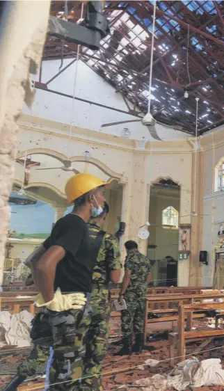  ??  ?? 0 Security personnel inspect the interior of St Sebastian’s Church in Negombo a