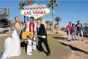  ?? Genaro Molina Los Angeles Times ?? E LV I S entertaine­r Mark Rumpler poses with Brazilian visitors Silvia and Paulo Castilho. For some tourists, visiting Las Vegas so soon after the Oct. 1 shooting rampage would feel inappropri­ate, a survey found.