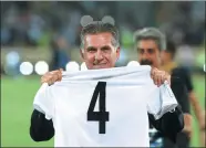  ?? VAHID SALEMI / AP ?? Iran coach Carlos Queiroz holds a shirt displaying the number of times he has qualified teams for the World Cup, following successes with South Africa (2002), his native Portugal (2010) and Iran (2014). Iran’s 2-0 win over Uzbekistan at Azadi Stadium...