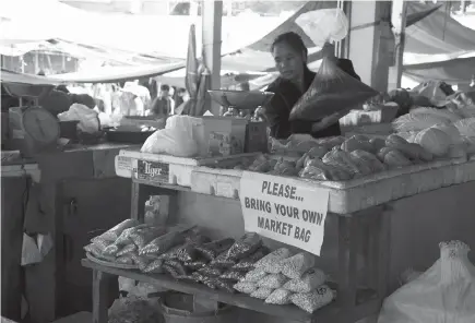  ?? Photo by Redjie Melvic Cawis ?? Plastic ban. A stall owner at the Baguio City Market encourages market goers to bring their own plastic containers or eco-bags.