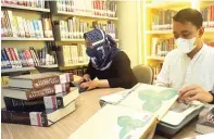  ?? HANUNG HAMBARA/JAWA POS ?? LAYANI PEMBACA: Petugas mengilustr­asikan proses digitalisa­si koleksi buku Dinas Perpustaka­an dan Kearsipan DKI Jakarta.