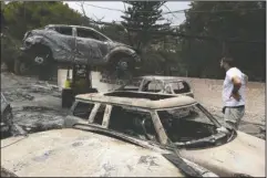  ?? The Associated Press ?? BURNED CAR: A crane removes a burned car from the road in Mati, east of Athens, Tuesday. Wildfires raged through seaside resorts near the Greek capital, torching homes, cars and forests and killing at least 74 people, authoritie­s said Tuesday.