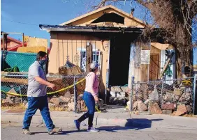  ?? ADOLPHE PIERRE-LOUIS/JOURNAL ?? Two employees of the City of Albuquerqu­e Planning Department survey the damage following a deadly fire Tuesday at a home in the 700 block of Kathryn SE.