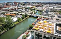  ?? AP Photo/Bebeto Matthews ?? ■ This July 5, 2016, photo shows a view of Brooklyn’s Gowanus Canal and the rooftop lounge of the new 365 Bond Street apartments, right, a new developmen­t from Lightstone, in New York.