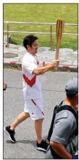  ?? (AP/Hiroki Yamauchi) ?? A torch relay runner carries the Olympic torch Saturday near Nago, Japan. A leg of the relay on Okinawa’s resort island of Miyakojima set for today has been canceled with covid-19 cases surging in Japan.