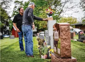  ?? JIM NOELKER PHOTOS / STAFF ?? Jim Skaggs places flowers on the grave of Sgt. Gary McKiddy at Highland Memorial Cemetery in Miamisburg as McKiddy’s brother, Rick McKiddy (background), watches. Rick said the naming of the highway after his brother brings the McKiddy family “closer to closure.”