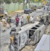 ?? PTI ?? Police and residents walk past charred remains of vehicles vandalised by a mob over a social media post in Bengaluru on Wednesday.