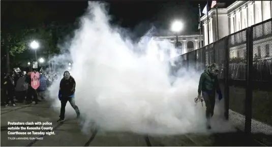  ?? TYLER LARIVIERE/SUN-TIMES ?? Protesters clash with police outside the Kenosha County Courthouse on Tuesday night.