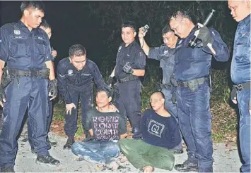  ??  ?? NO ESCAPE: The suspects in the custody of police patrolmen at the constructi­on site at Taman Uni Garden in Kota Samarahan.