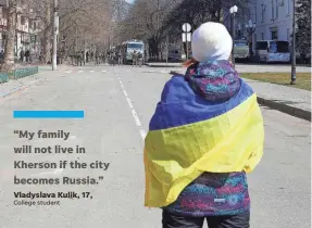  ?? OLEXANDR CHORNYI/AP ?? A woman wrapped in a Ukrainian flag stands in front of Russian troops during a protest against the occupation of Kherson on March 19.