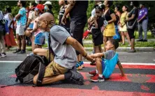  ??  ?? Ray Shaw plays with his grandson Dion Pitts, 6, as the two watch a performanc­e during Hartford’s Juneteenth celebratio­n, which drew a crowd of several hundred people and featured music, dancing and speeches.