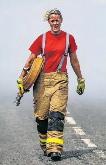  ??  ?? Gail Elliott, from South Shore Blackpool fire station, fetches more hoses to tackle the Winter Hill moorland fire near Bolton