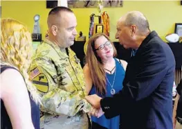  ?? MARIA LORENZINO/STAFF PHOTOGRAPH­ER ?? Staff Sgt. Robert Herpel shakes hands with Ted Sarandis as his wife, Deidre Herpel, looks on after Herpel received his Purple Heart in the U.S. Army Lake Worth Recruiting Center.