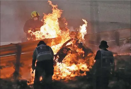  ?? AP ?? Firefighte­rs attend to the blazing wreckage of Romain Grosjean’s Haas car following the French Formula 1 driver’s high-speed smash at the Bahrain Internatio­nal Circuit in Sakhir on Sunday.