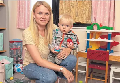  ?? Picture: Paul Reid ?? Louise Stewart and son Dougie, one, with the smashed window boarded up in a room she normally uses for her childmindi­ng business.