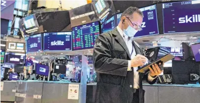  ?? Colin Ziemer The Associated Press ?? Trader Edward Curran works Thursday on the floor of the New York Stock Exchange. Stocks rose as investors remain optimistic that Washington will deliver another round of economic stimulus money as vaccines begin rolling out to the public.