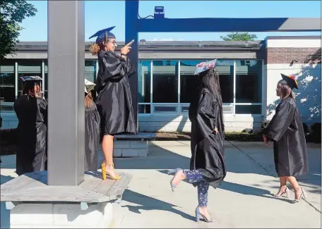  ?? SARAH GORDON/THE DAY ?? Sierra Talley, left, stands on a bench to take a photo of Angela Chen’s mortarboar­d before Montville High School’s commenceme­nt on Monday. Go to www.theday.com for a list of the Montville High graduates and a photo gallery.