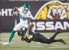 ?? The Canadian Press ?? Saskatchew­an Roughrider­s’ Caleb Holley tries to break the tackle of Hamilton Tiger-Cats’ Richard Leonard during second-half CFL action in Hamilton, Ont., on Thursday night.