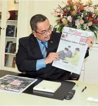  ??  ?? New chapter: sanusi looking at the front page picture of ‘The star’ newspaper at his office in Wisma darul aman in alor setar.