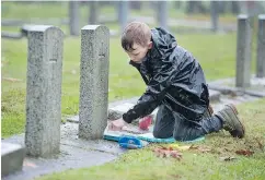  ?? PHOTOS: JASON PAYNE/PNG ?? Volunteers, including Nathalie Ralston, 9, left, and Kai Harrison, 8, braved the rain on Saturday to clean the moss and debris from the graves of fallen soldiers at Fraser Cemetery in New Westminste­r.