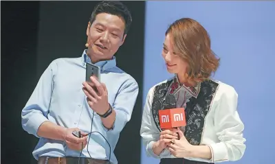  ?? FENG YONGBIN / CHINA DAILY ?? Lei Jun, CEO of Xiaomi Corp, tries Redmi Pro, a new Xiaomi handset released on Wednesday in Beijing, while actress Liu Shishi looks on.