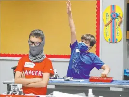  ?? The Associated Press ?? Amid concerns about the spread of COVID-19, Aiden Trabucco, right, wears a mask July 14 as he raises his hand to answer a question behind Anthony Gonzales during a summer STEM camp at Wylie High School in Wylie, Texas.