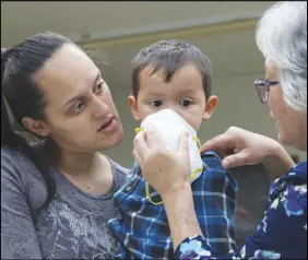  ?? AP PHOTO ?? Lindsey Magnani and her son Kahele Rodrigues listen as an official shows them how to use a respirator that was given to them to help protect against ash from Kilauea volcano.