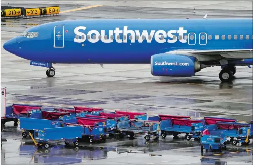  ?? MATT YORK AP FILE PHOTO ?? A Southwest Airlines jet passes unused luggage carts as it arrives, Dec. 28, 2022, at Sky Harbor Internatio­nal Airport in
Phoenix. The U.S. Transporta­tion Department said Wednesday it is investigat­ing whether Southwest Airlines deceived customers by knowingly scheduling more flights in late December than it realistica­lly could handle.