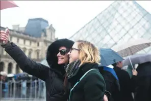  ?? KAMIL ZIHNIOGLU / ASSOCIATED PRESS ?? Two women take a selfie as they wait to enter the reopened Louvre museum on Saturday, less than 24 hours after the attack.