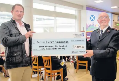  ??  ?? Good effort Glasgow Airport chaplain Keith Banks hands over a cheque to a representa­tive of the British Heart Foundation