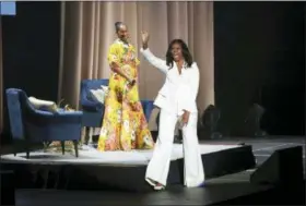  ?? PHOTO BY WILLY SANJUAN — INVISION — AP ?? Former first lady Michelle Obama greets the audience as Tracee Ellis Ross watches at the “Becoming: An Intimate Conversati­on with Michelle Obama” event at the Forum on Thursday in Inglewood