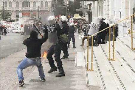  ?? Thanassis Stavrakis / Associated Press ?? A protester with a hammer attacks a riot police officer in a clash in Athens during a nationwide general strike demonstrat­ion.