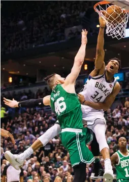  ??  ?? MILWAUKEE BUCKS forward Giannis Antetokoun­mpo dunks over Boston Celtics center Aron Baynes for two of his 19 points in the Bucks’ 116-92 home victory over the Celtics on Friday night in Game 3 of the teams’ first-round Eastern Conference playoff series.