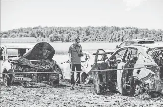  ?? TARA WALTON THE CANADIAN PRESS ?? An investigat­or examines the wreckage the day after a fire on Sunday that caused more than $1 million in damage to 34 vehicles parked in a hay field for the Niagara Lavender Festival.
