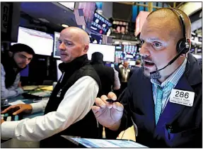  ?? AP/RICHARD DREW ?? Trader Michael Milano (right) works on the floor of the New York Stock Exchange on Thursday as U.S. stocks moved lower in early trading before rallying in the afternoon to close in positive territory.