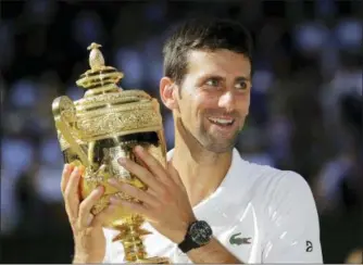  ?? BEN CURTIS — THE ASSOCIATED PRESS ?? Novak Djokovic of Serbia holds the trophy after defeating Kevin Anderson of South Africa in the men’s singles final match at the Wimbledon Tennis Championsh­ips in London, Sunday.