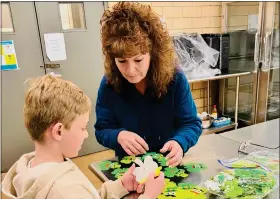  ?? JENNIFER MEYERS - COURTESY PHOTO ?? Michelle Grady, right, and 8-year-old Oliver Meyers look through his shamrock crafts at Meals on Wheels in Loveland March 7. Meyers said he was proud of the work he did and thought getting to see the MOW kitchen was cool.